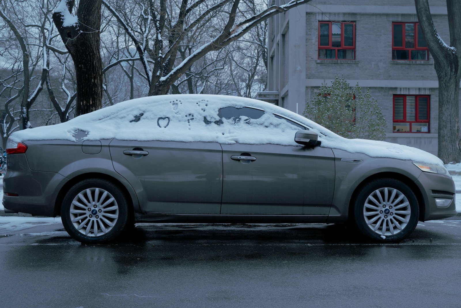 a car covered in snow parked in front of a building