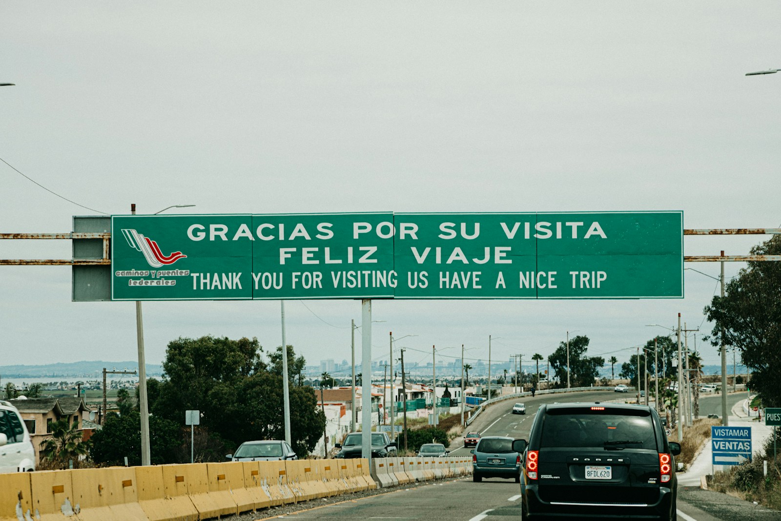 black vehicle on road with gracias por su visita feliz viaje signage